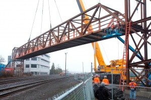 A 70-ton, 184-foot pedestrian/bike span is lifted into place over the Union Pacific Railroad tracks.