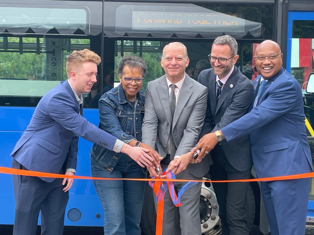 From left: Mayor Rory Bialostosky of West Linn, Mayor Denyse McGriff of Oregon City, Clackamas County Commissioner Paul Savas, Mayor Joe Buck of Lake Oswego and TriMet General Manager Sam Desue Jr. cut an orange ribbon in front of a TriMet bus with the message "Moving forward together."