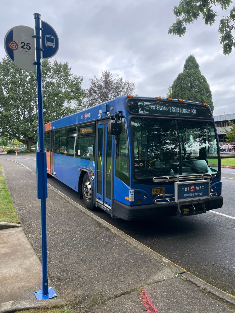 A blue and orange TriMet bus serves Line 25-Glisan/Troutdale Rd's stop at the Mt. Hood Community College campus.