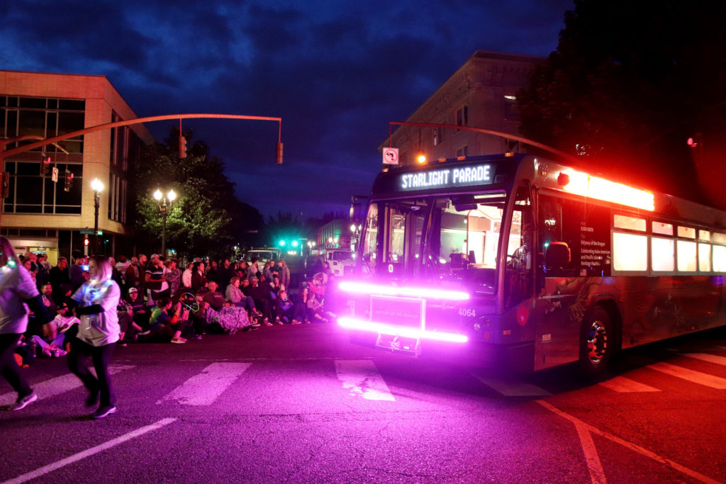 Image of a TriMet bus decorated with lights, with the header "Starlight Parade," on the parade route in Downtown Portland.