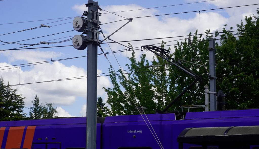 Image of Tensorex tensioning devices on overhead wires at the Gresham Central Transit Center. A TriMet MAX train is visible at the bottom of the frame.